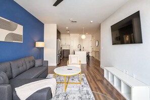 A modern living room with a sofa, a coffee table, and a TV mounted on the wall.