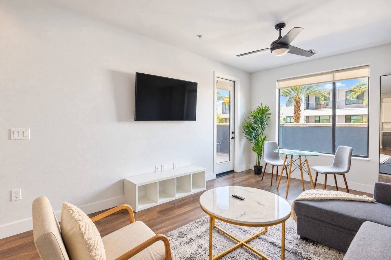 A modern living room with a flat-screen TV, a glass-top coffee table, and a sofa.