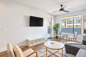 A modern living room with a flat-screen TV, a glass-top coffee table, and a sofa.