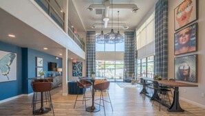 A spacious, modern hotel lobby with high ceilings, a mezzanine level, and a large dining area with contemporary furniture. - Centrally Located Apt|Pool,Gym,W/D,Balcony,Parking (Tempe)