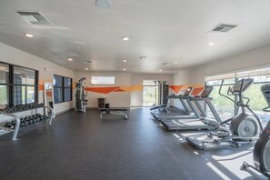 A gym with treadmills, elliptical machines, and a rack of dumbbells.