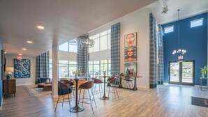 A spacious lobby with high ceilings, large windows, and a mix of seating areas including a bar and a dining space. - Centrally Located Apt|Pool,Gym,W/D,Balcony,Parking (Tempe)