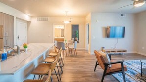 A modern kitchen with a marble countertop, bar stools, and a dining area with chairs. - Centrally Located Apt|Pool,Gym,W/D,Balcony,Parking (Tempe)