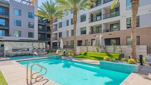 Un hôtel moderne doté d’une piscine, de palmiers et d’un jardin bien entretenu.
