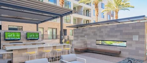 An outdoor bar area with seating and a TV screen.