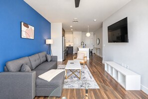 A modern living room with a grey sofa, a coffee table, and a TV mounted on the wall.