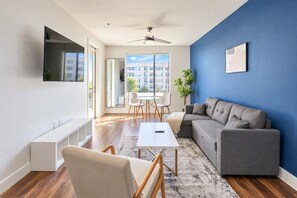 A modern living room with a grey sofa, a white coffee table, and a TV mounted on the wall.