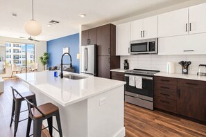 A modern kitchen with a central island, stainless steel appliances, and a view to the outside. - DT Tempe 1BD with  Pool Gym Parking WD (Tempe)