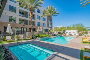 A pool area with multiple swimming pools, lounge chairs, and palm trees.