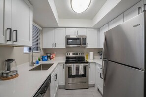 Una cocina moderna con armarios blancos, electrodomésticos de acero inoxidable y horno empotrado.