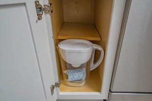 Un inodoro compacto con tanque transparente y un estante de madera encima.
