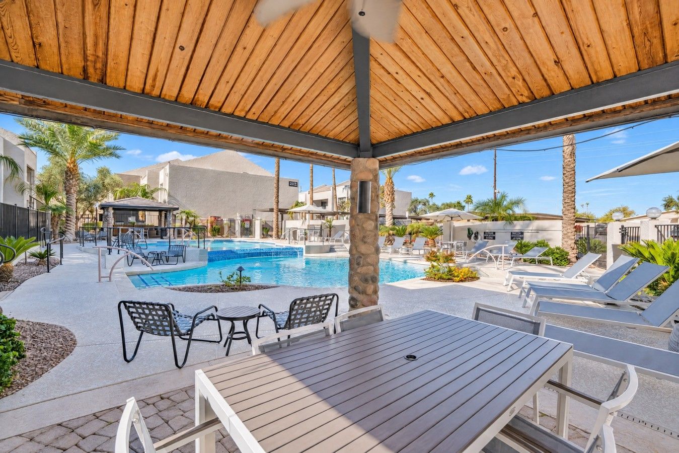Area piscina con lettini, un pontile in legno e una zona relax coperta.