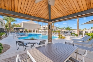 A pool area with lounge chairs, a wooden deck, and a covered seating area.