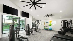 Kuntosali, jossa on kuntoiluvälineitä, suuret ikkunat ja näkymä ulos.