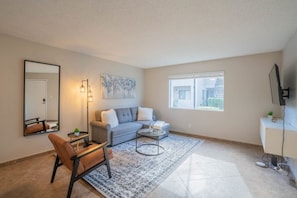 A modern living room with a sofa, coffee table, and a large mirror.