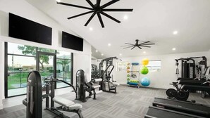 Un gimnasio moderno con diversos equipos de ejercicio, ventanas amplias y vistas al exterior.