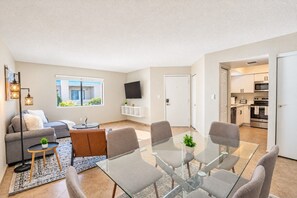 A modern apartment with a living room, dining area, and kitchen.