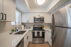 A modern kitchen with stainless steel appliances, white cabinetry, and a built-in oven.