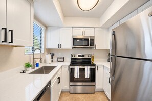 Una cocina moderna con armarios blancos, electrodomésticos de acero inoxidable y horno empotrado.