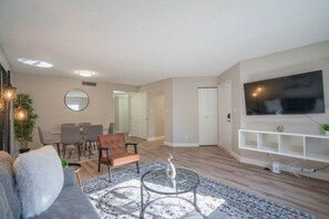 A modern living room with a sofa, coffee table, and a TV mounted on the wall. - Walk to Old Town Gym, Pool, WD, Pkg  Balcony (Scottsdale)