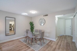 A dining area with a glass table and chairs, a potted plant, and a mirror on the wall. - Walk to Old Town Gym, Pool, WD, Pkg  Balcony (Scottsdale)