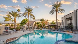 A swimming pool with lounge chairs and palm trees, surrounded by buildings. - Walk to Old Town Gym, Pool, WD, Pkg  Balcony (Scottsdale)