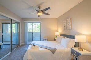 A hotel room with a bed, bedside lamps, a ceiling fan, and a sliding glass door leading to a balcony. - Walk to Old Town Gym, Pool, WD, Pkg  Balcony (Scottsdale)