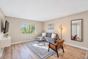 A living room with a sofa, armchair, coffee table, and a large window.