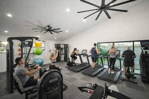 A gym with various exercise equipment, including treadmills, a rowing machine, and free weights.