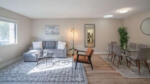 A modern living room with a gray sofa, a glass coffee table, and a dining area with a glass table and chairs. - Walk to Old Town Gym, Pool, WD, Pkg  Balcony (Scottsdale)