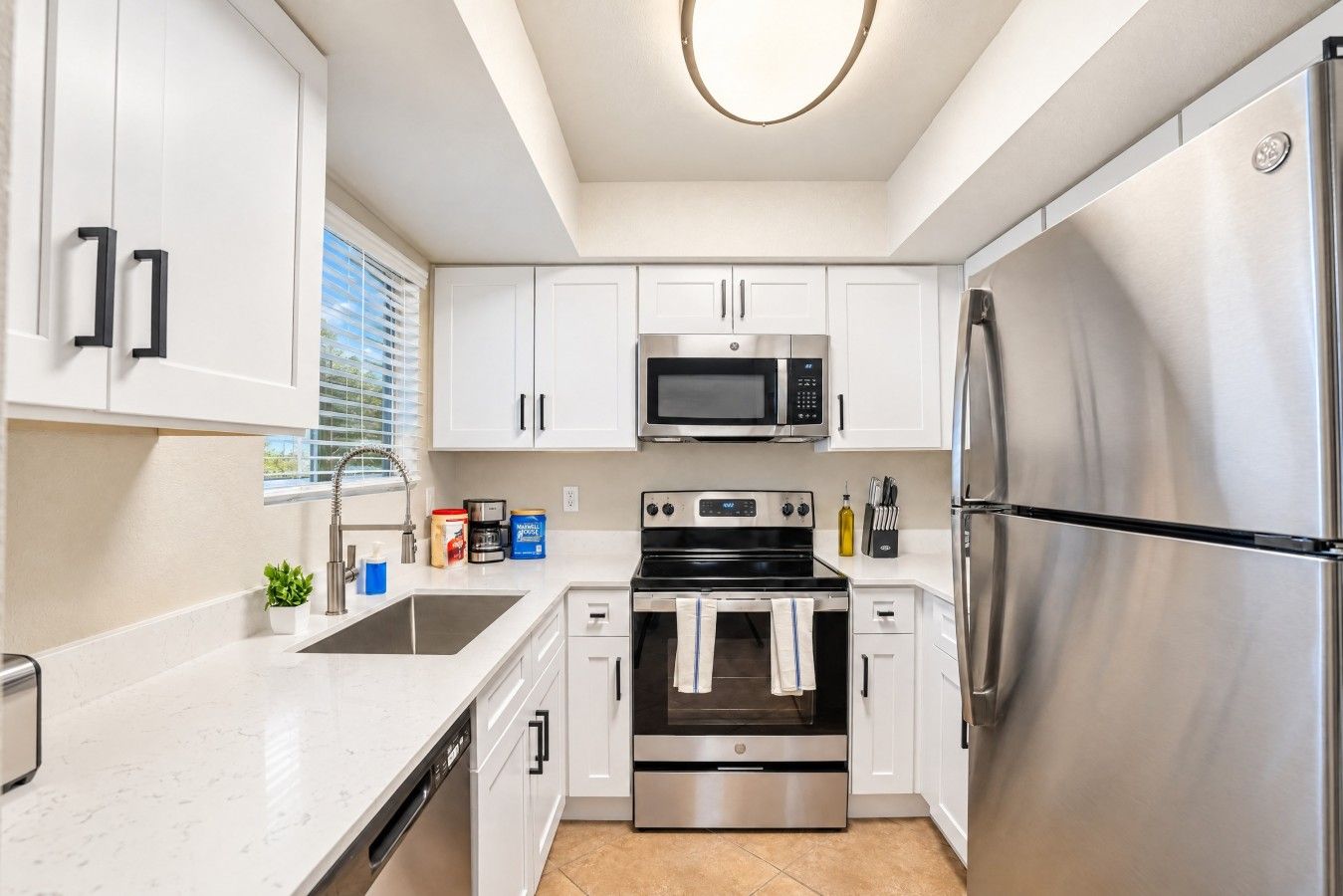 A modern kitchen with white cabinets, stainless steel appliances, and a built-in oven.