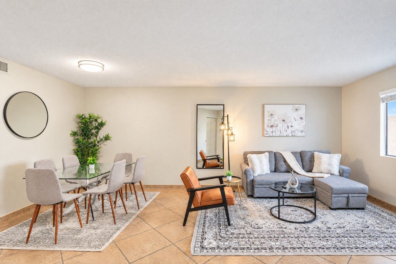 A modern living room with a dining area, a sofa, a coffee table, and a large mirror.