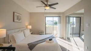Ein Hotelzimmer mit Bett, Deckenventilator und Blick ins Freie durch eine Schiebetür.