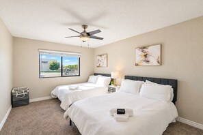 A hotel room with two beds, a ceiling fan, a window with a view, and artwork on the walls. - Near DT & Trails | Pool,Gym,Balcony,W/D,Parking (Scottsdale)