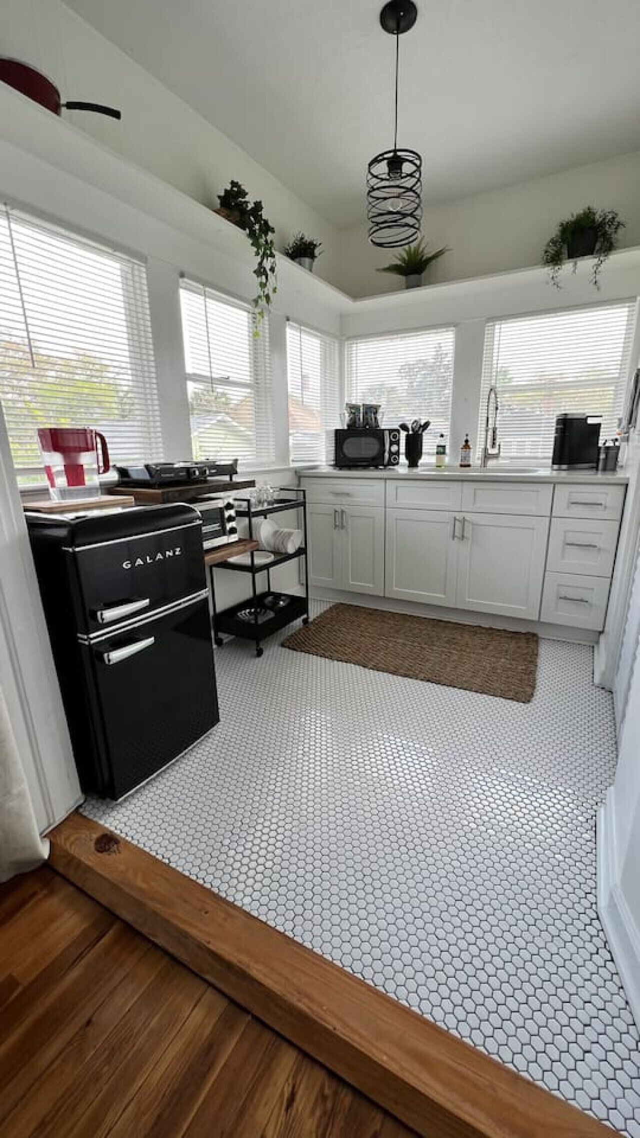 A kitchen with white cabinets, a black stove, and a hexagonal patterned floor.