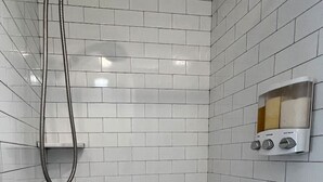 Een douche met een handdouche en bedieningspaneel aan de muur.