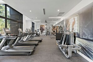 Een fitnessruimte met loopbanden, hometrainers en krachtapparaten.