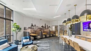 Ein zeitgemäßer Essbereich mit einem langen Tisch, Stühlen, einem blauen Sofa und einem runden Couchtisch.