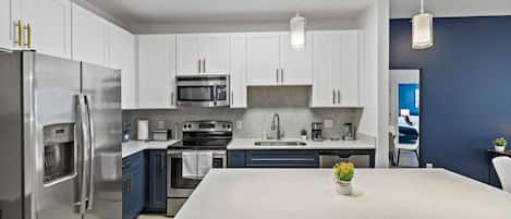 Una cocina moderna con electrodomésticos de acero inoxidable, una isla central y vistas a un dormitorio.
