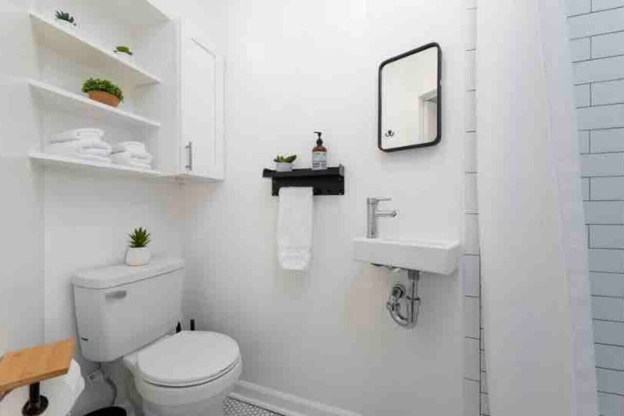 A modern bathroom with a toilet, sink, and shelves with plants.