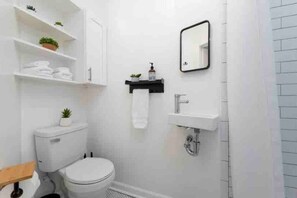 A modern bathroom with a toilet, sink, and shelves with plants. - Bright Airy Luxurious Abode in Walkable Riverside (Jacksonville)