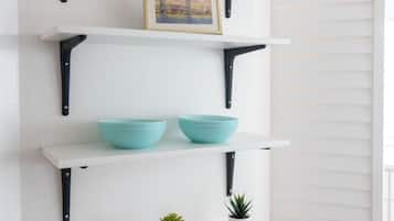 A white wall with a black metal shelving unit holding various items.