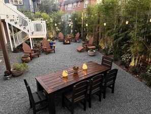 A patio with a wooden table and chairs, surrounded by potted plants and a fire pit. - Bright Airy Luxurious Abode in Walkable Riverside (Jacksonville)