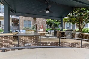 Un espace extérieur aménagé en terrasse, avec un mur en briques, un barbecue et des sièges.
