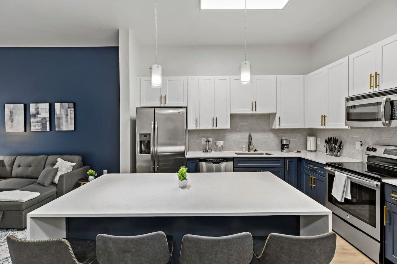 Une cuisine moderne dotée d’un îlot central, d’appareils électroménagers en acier inoxydable et d’un mur d’accent bleu.