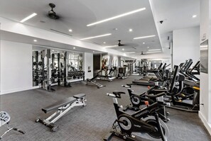 Une salle de sport équipée de divers appareils d’exercice, notamment des tapis de course, des vélos d’appartement et des appareils de musculation.