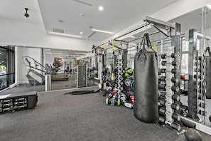 A gym with various exercise equipment, including a punching bag, weight racks, and cardio machines. - Near CPCC & light Rail | Pool, Gym, W/D & Parking (Charlotte)