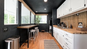 A modern kitchen with a wooden countertop, white cabinets, and a black ceiling. - Wabi-Sabi Inspired Studio w Bikes, Walk to River (Jacksonville)