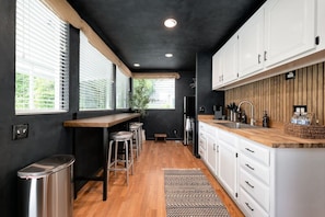 A modern kitchen with a wooden countertop, white cabinets, and a black ceiling. - Wabi-Sabi Inspired Studio w Bikes, Walk to River (Jacksonville)