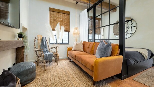 Una sala de estar moderna con un sofá, sillas, chimenea y un ventanal con persianas.